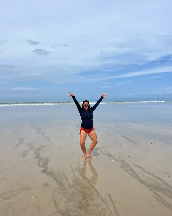 Julie Santos en la playa con los brazos en alto